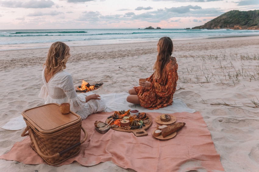 deux filles en train de manger sur la plage autour dun feu deux filles en train de manger sur la plage autour dun feu