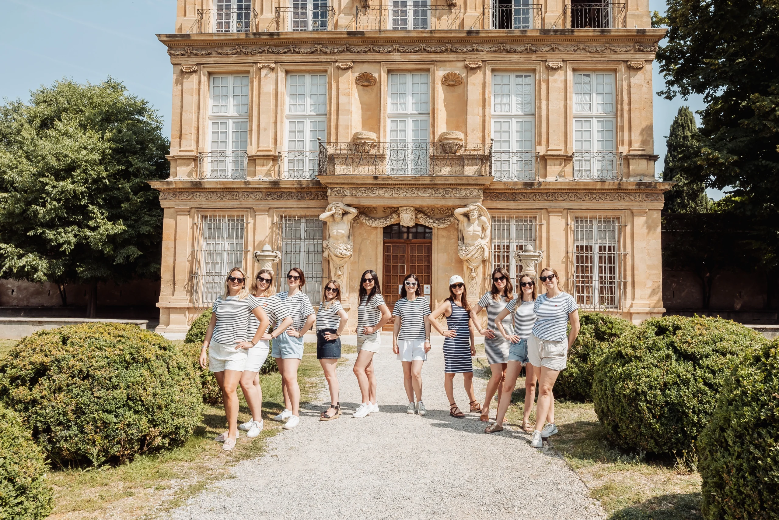 Groupe de femmes en tenue marinière posant en ligne devant un bâtiment historique à Aix-en-Provence pendant un EVJF.