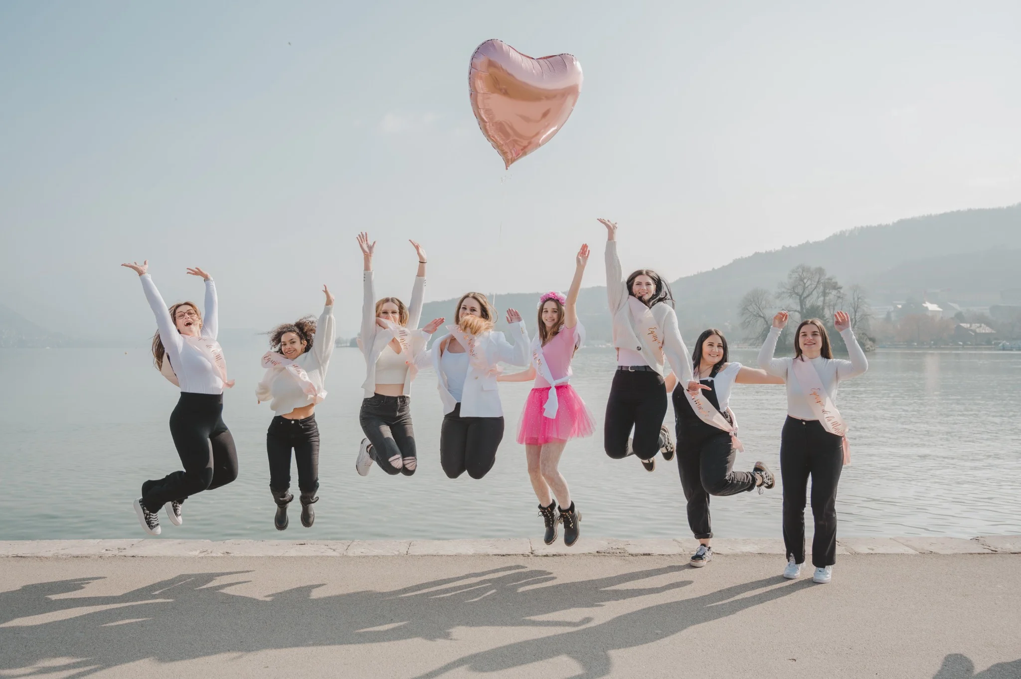 Enterrement de vie de jeune fille à Annecy : groupe de filles sautant devant le lac, ambiance festive dans l'une des meilleures destinations EVJF en France.