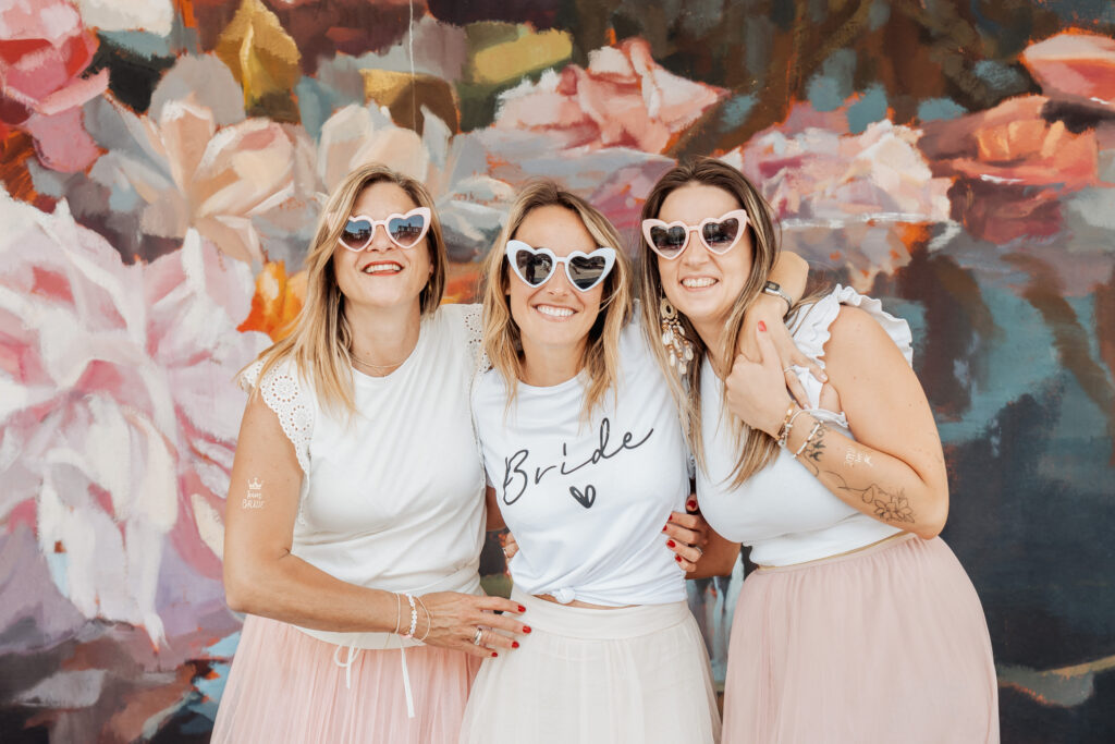 Future mariée et ses amies devant un mur fleuri à Arcachon lors d'un EVJF en été.