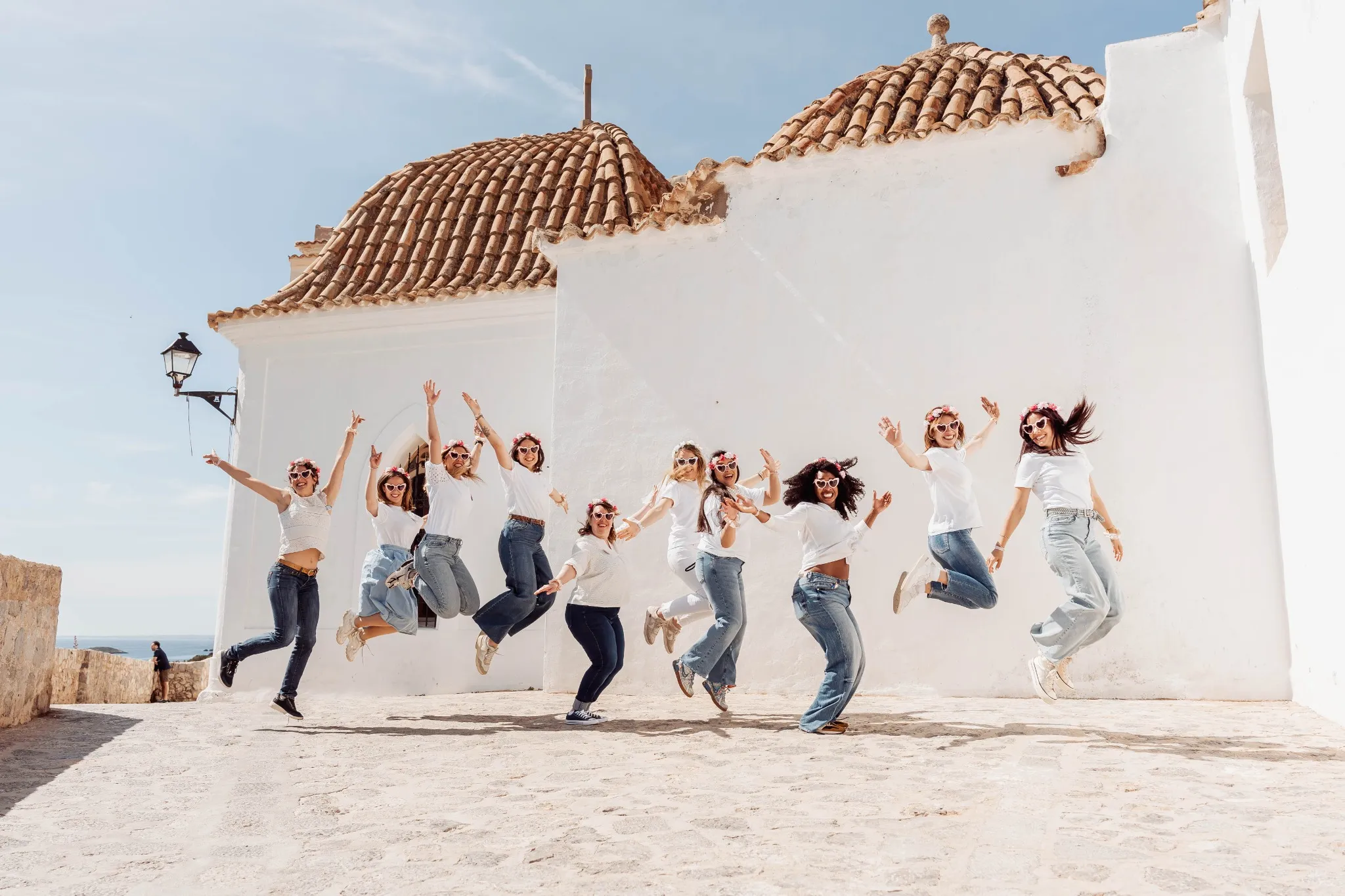 Photo de groupe EVJF à Ibiza sautant en l'air dans une ruelle ensoleillée
