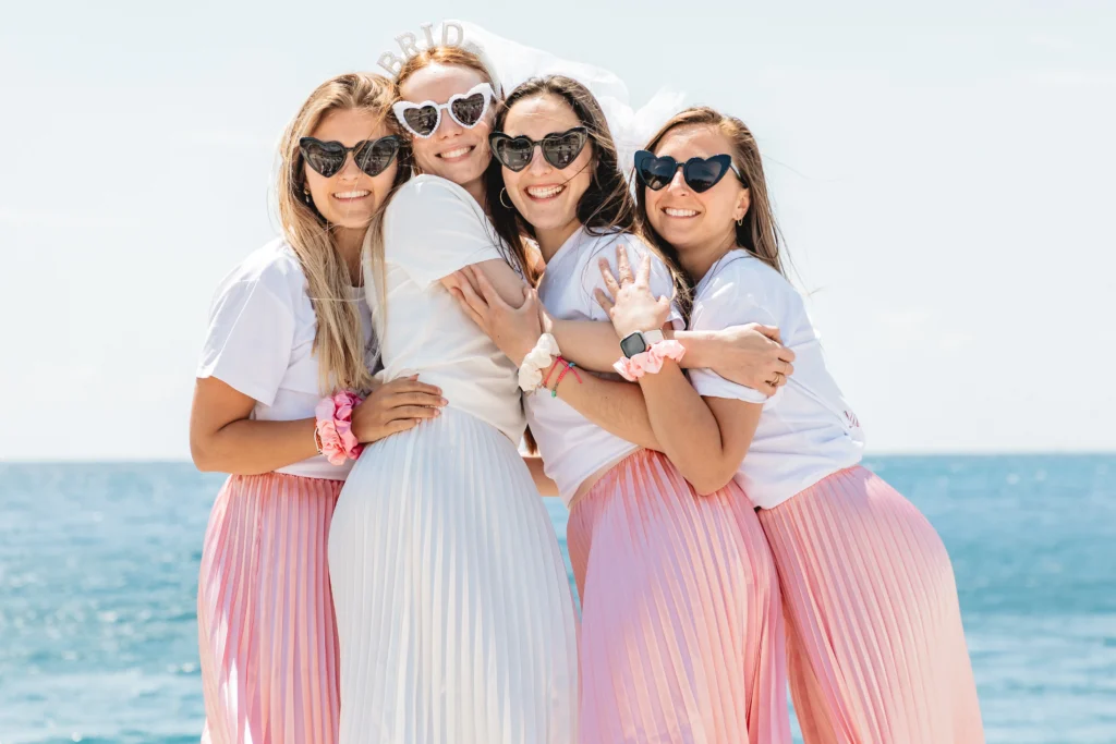 organiser un evjf a nice EVJF à Nice – La mariée partage un moment de tendresse avec sa team bride en jupes roses sur la plage