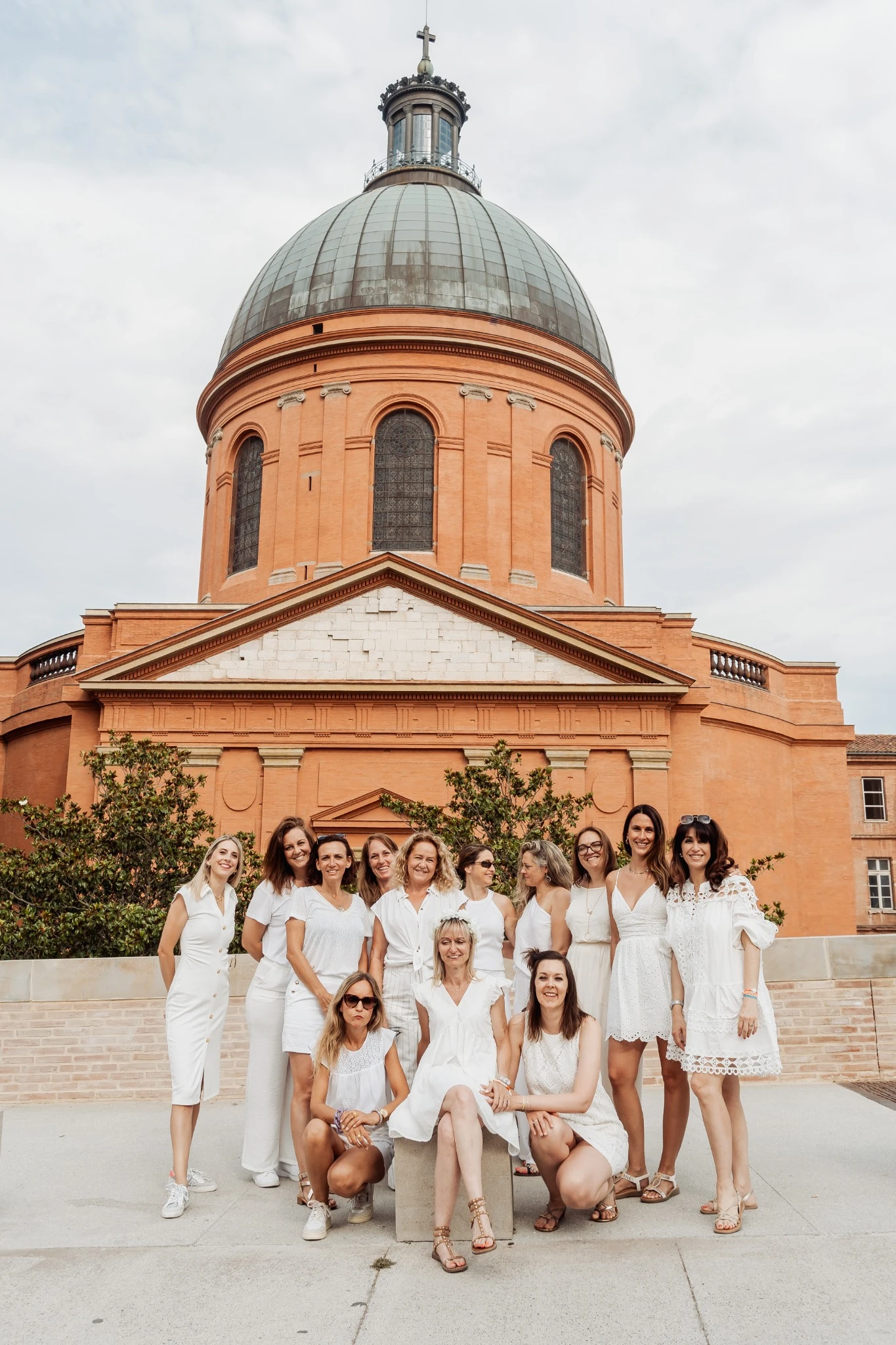 Groupe de femmes en blanc devant la coupole de La Grave à Toulouse lors d’un EVJF, ambiance joyeuse et élégante.