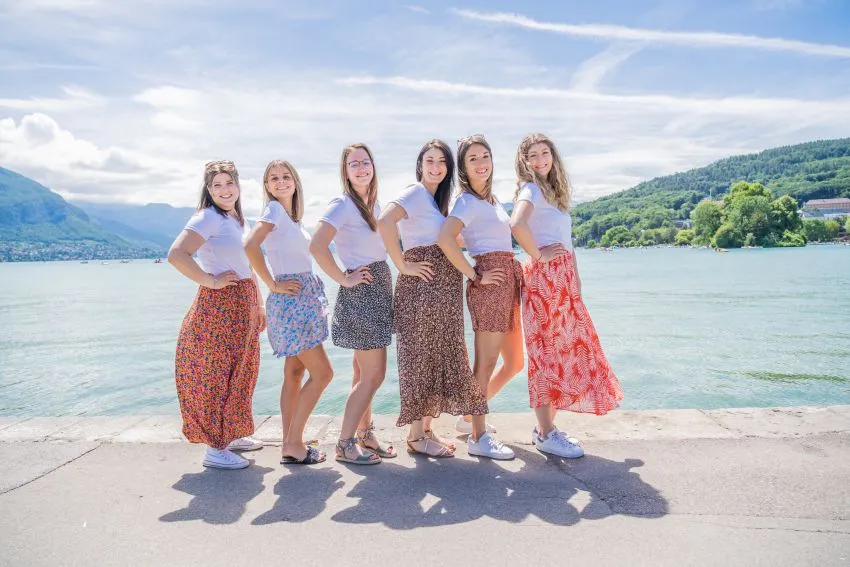 Shooting photo EVJF à Chambéry au bord du lac : une séance pleine de fun et d’amitié Séance photo EVJF à Chambéry : groupe de femmes posant avec des jupes colorées devant le lac du Bourget