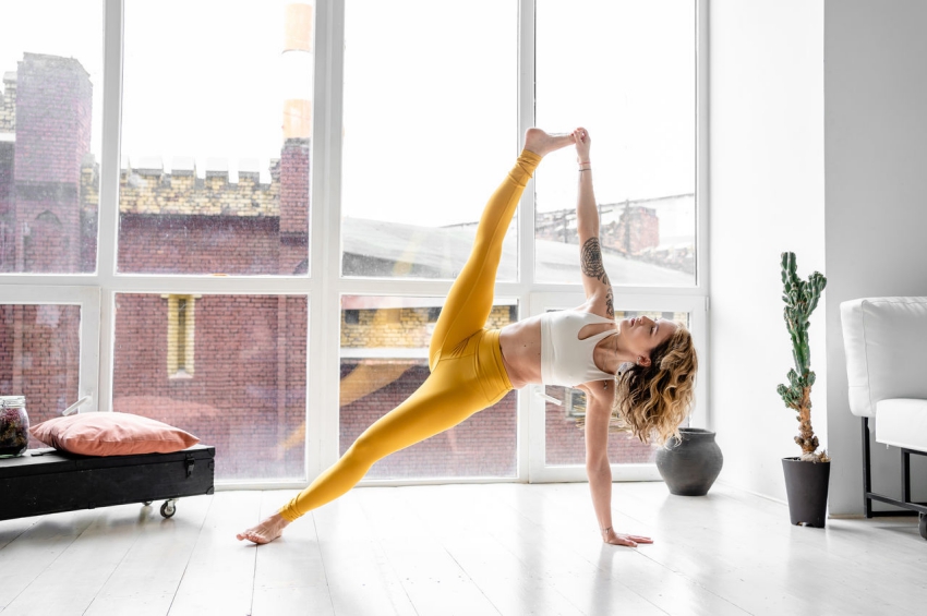 femme qui fait du yoga dans son appartement en face de la fenetre