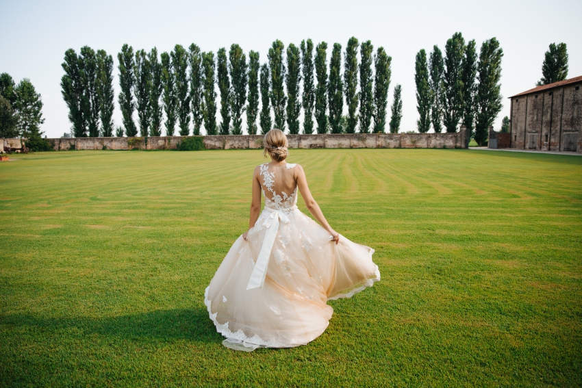 jeune femme en robe de mariee qui court dans un jardin