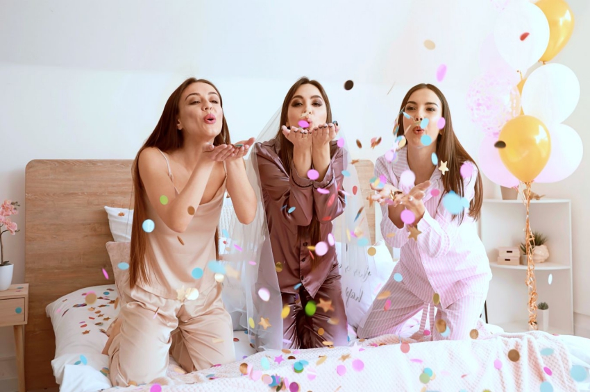 trois filles sur un lit qui souffle sur des confettis